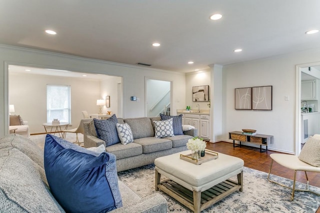 living area with recessed lighting, visible vents, wood finished floors, and ornamental molding