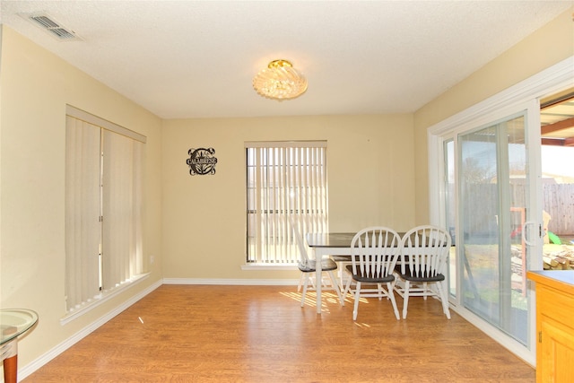 dining room with light wood-type flooring, baseboards, and visible vents