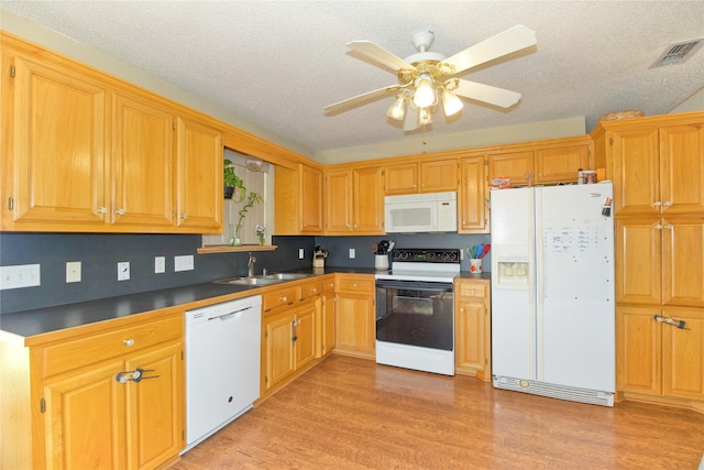 kitchen with dark countertops, visible vents, light wood-style flooring, a sink, and white appliances