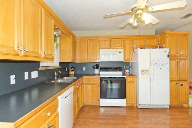 kitchen with dark countertops, visible vents, light wood-style floors, a sink, and white appliances