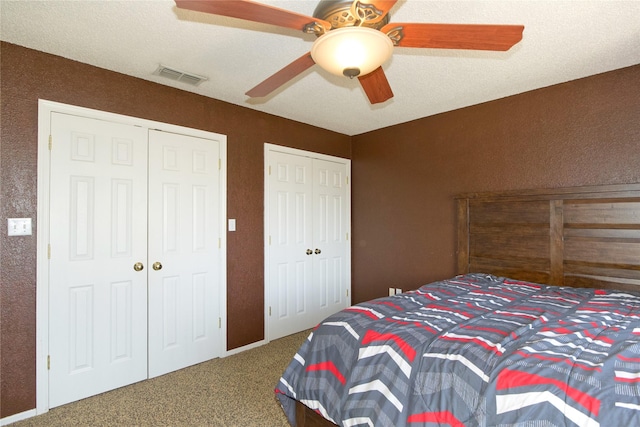 carpeted bedroom featuring ceiling fan, visible vents, and multiple closets