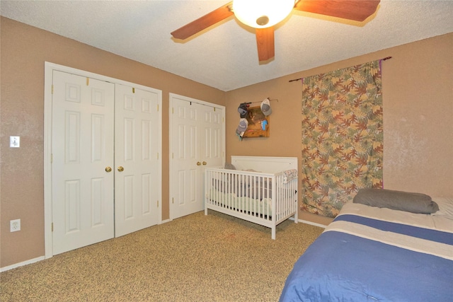 bedroom featuring multiple closets, carpet, ceiling fan, and a textured ceiling