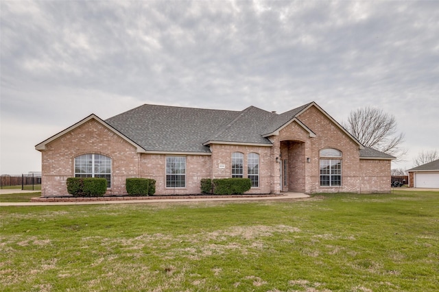 french provincial home featuring brick siding, a shingled roof, and a front yard