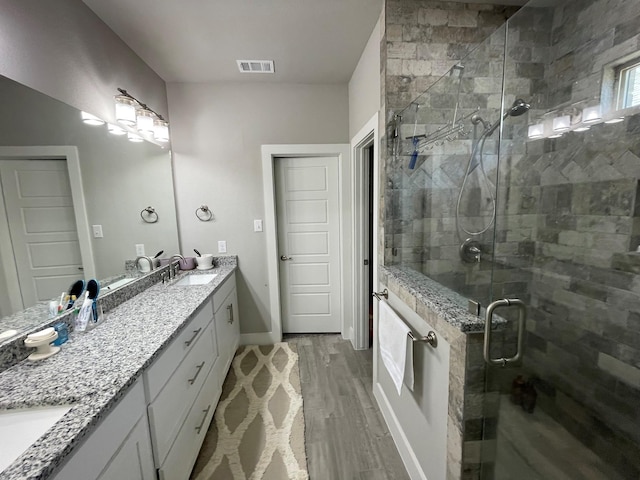 bathroom featuring visible vents, a stall shower, vanity, wood finished floors, and baseboards