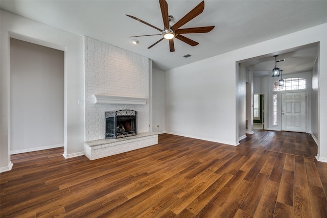 unfurnished living room featuring a brick fireplace, wood finished floors, visible vents, and baseboards