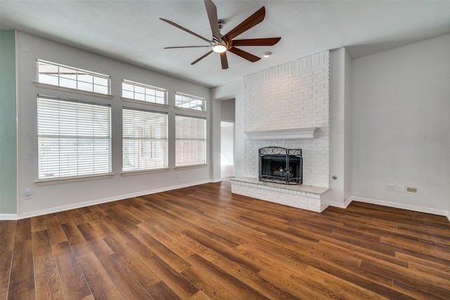 unfurnished living room featuring a healthy amount of sunlight, a brick fireplace, baseboards, and wood finished floors