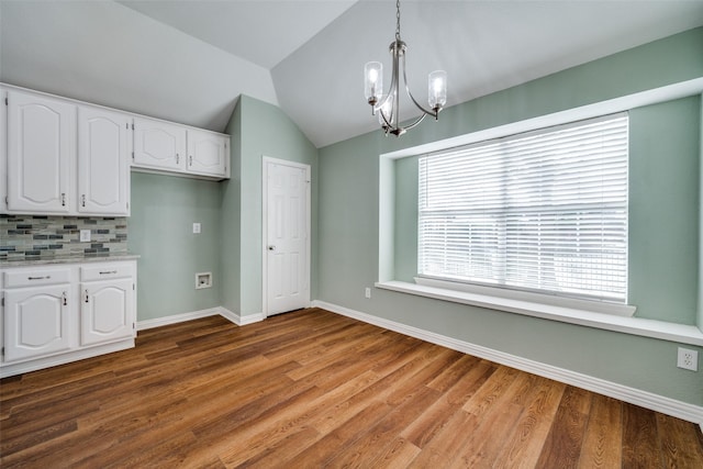 kitchen featuring decorative light fixtures, tasteful backsplash, white cabinetry, vaulted ceiling, and wood finished floors