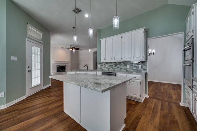 kitchen featuring decorative backsplash, a brick fireplace, a sink, and white cabinets