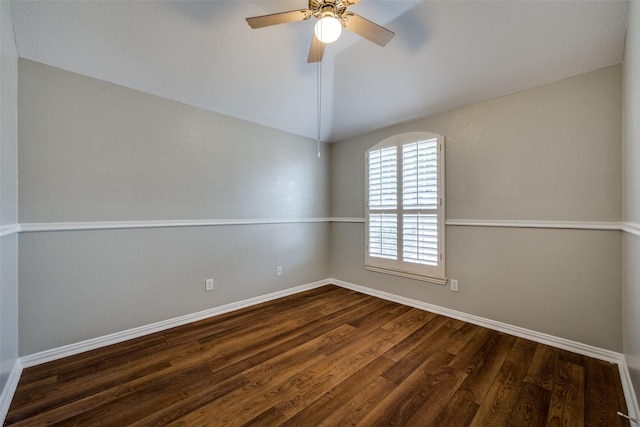 empty room with baseboards, a ceiling fan, vaulted ceiling, and dark wood-type flooring