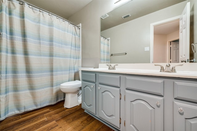 bathroom with double vanity, visible vents, a sink, and wood finished floors