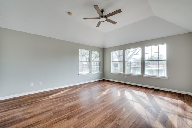 unfurnished room featuring lofted ceiling, dark wood-style floors, baseboards, and a ceiling fan