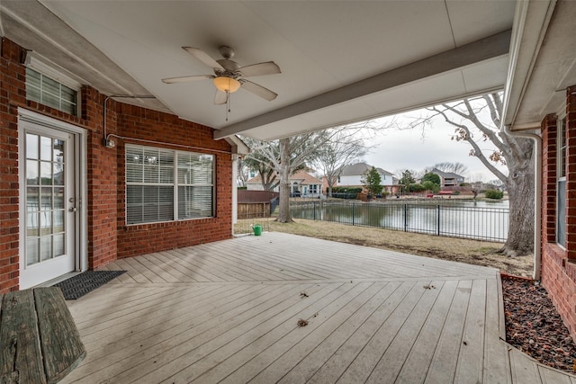 deck with ceiling fan, a water view, and a fenced backyard