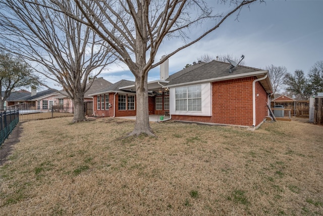 back of house with a patio, a fenced backyard, brick siding, a lawn, and a chimney