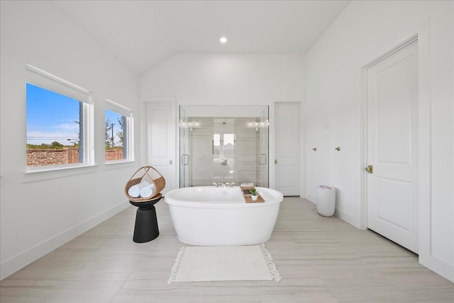 full bathroom featuring vaulted ceiling, a stall shower, a soaking tub, and baseboards