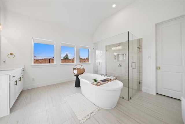 bathroom with a freestanding tub, vanity, baseboards, vaulted ceiling, and a stall shower