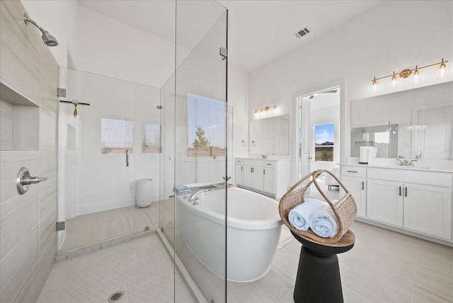 bathroom with visible vents, a freestanding tub, two vanities, and a shower stall