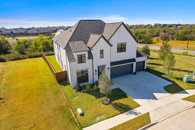 view of front of home with an attached garage, concrete driveway, roof with shingles, stucco siding, and a front lawn