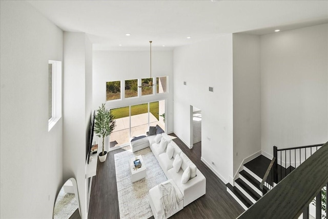 living area featuring dark wood-type flooring, recessed lighting, a towering ceiling, and baseboards