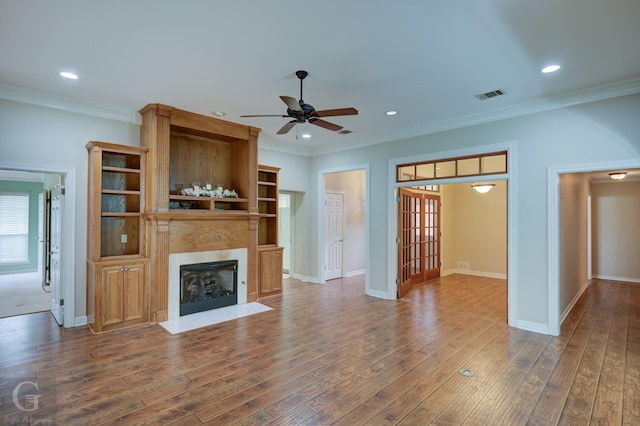 unfurnished living room featuring a fireplace, recessed lighting, wood-type flooring, visible vents, and ornamental molding