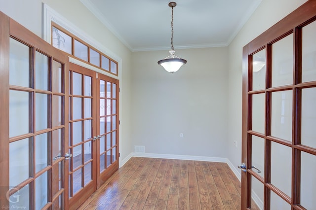 unfurnished room with french doors, crown molding, baseboards, and wood finished floors