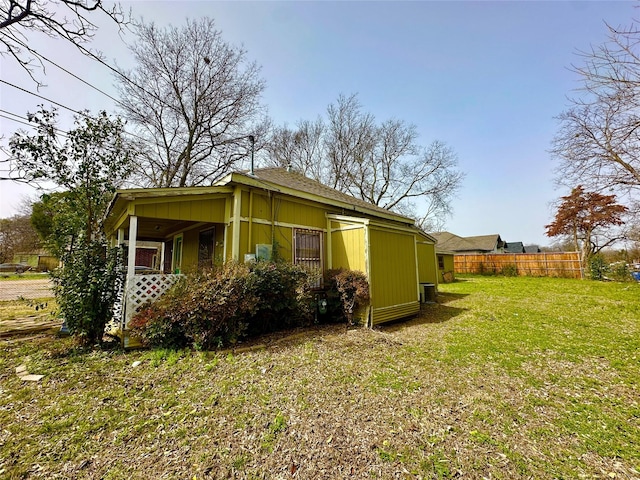 view of side of property with a lawn and fence