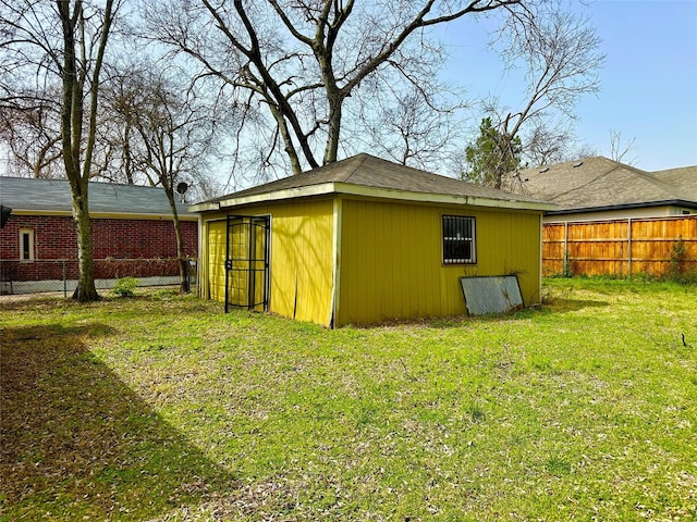 exterior space with brick siding, fence, an outdoor structure, and a yard