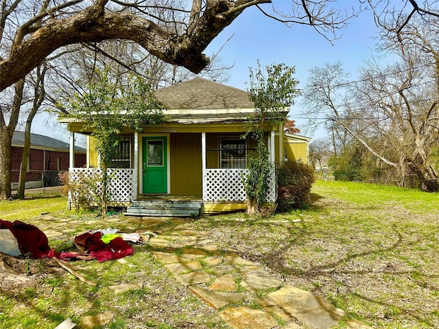 view of front of house with covered porch, a front lawn, and a shingled roof