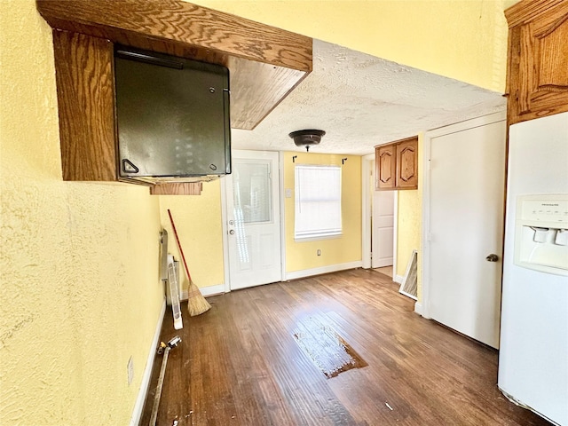 interior space with a textured ceiling, baseboards, and wood finished floors