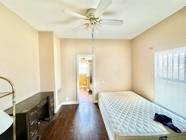 bedroom with a ceiling fan, visible vents, dark wood finished floors, and baseboards