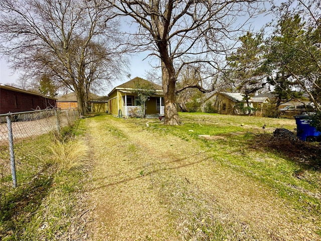 view of yard with fence and dirt driveway