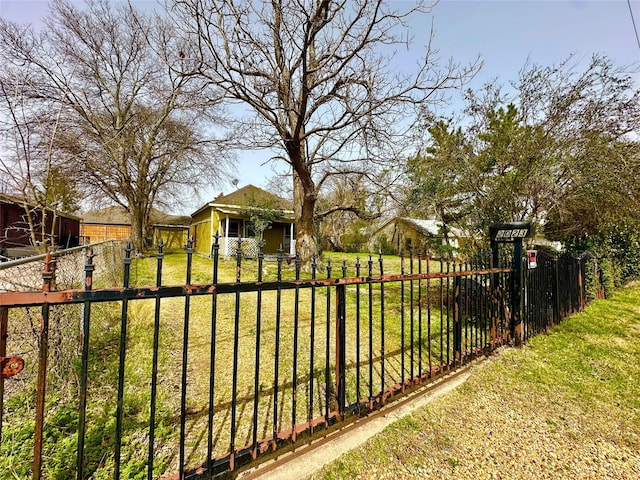 view of gate with a fenced front yard and a lawn