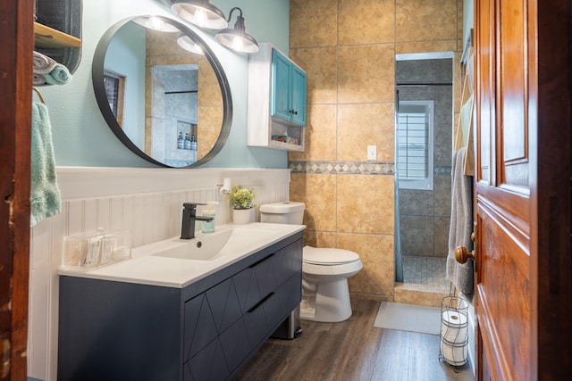 full bath featuring toilet, a wainscoted wall, wood finished floors, walk in shower, and vanity