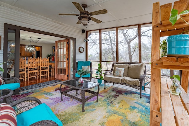 sunroom featuring ceiling fan with notable chandelier