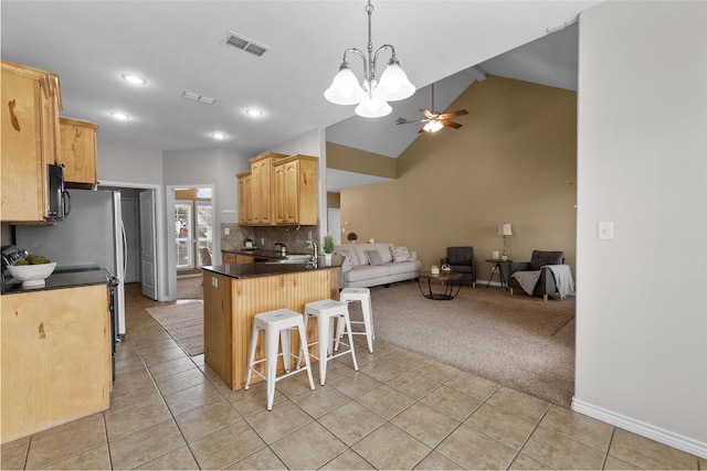 kitchen with light tile patterned floors, light colored carpet, a breakfast bar, visible vents, and open floor plan