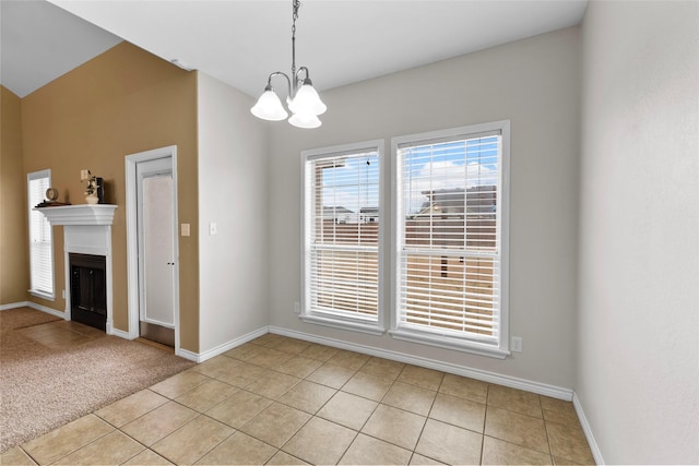 unfurnished dining area with a fireplace with flush hearth, a chandelier, light tile patterned flooring, and baseboards