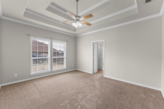 spare room with crown molding, a raised ceiling, light colored carpet, a ceiling fan, and baseboards