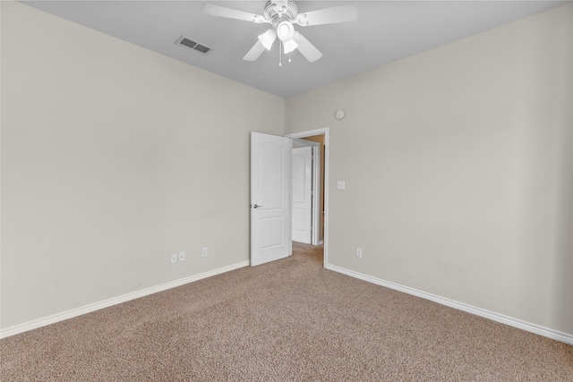 carpeted empty room with a ceiling fan, visible vents, and baseboards