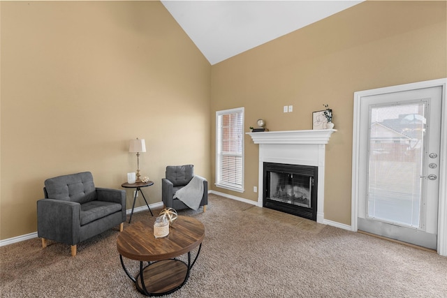 sitting room with carpet floors, high vaulted ceiling, a fireplace with flush hearth, and baseboards