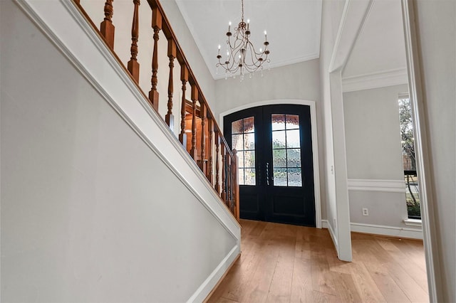 entryway with arched walkways, french doors, light wood-style flooring, baseboards, and stairs