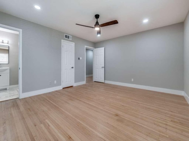 unfurnished bedroom featuring ensuite bath, baseboards, visible vents, and light wood-style floors