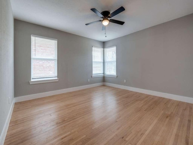empty room featuring baseboards, a ceiling fan, and light wood-style flooring