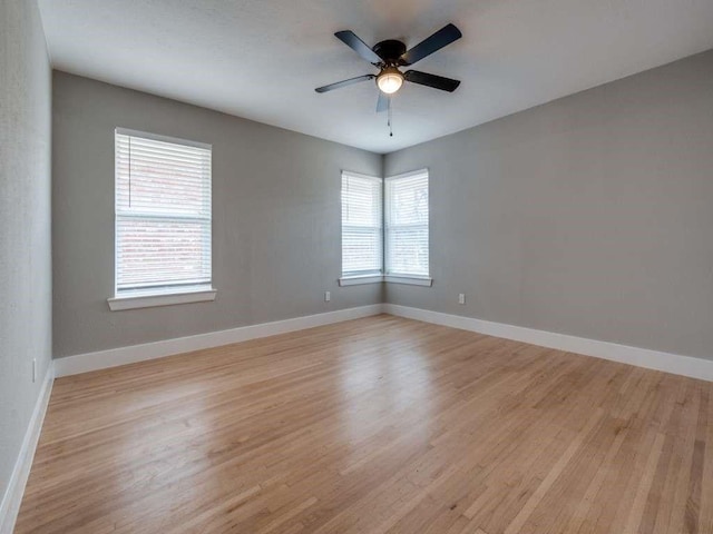 unfurnished room featuring ceiling fan, light wood-style floors, and baseboards