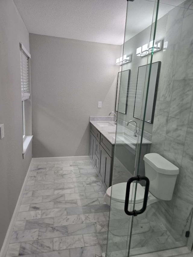 bathroom with double vanity, marble finish floor, a textured ceiling, and a shower stall