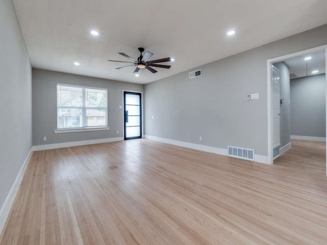 spare room with light wood finished floors, visible vents, and baseboards