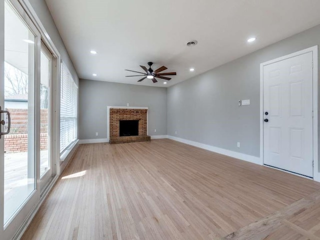 unfurnished living room featuring light wood-type flooring, a fireplace, visible vents, and baseboards