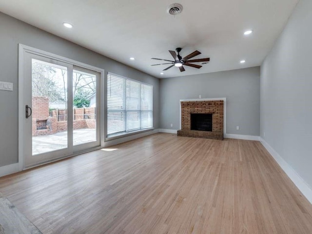 unfurnished living room featuring baseboards, visible vents, light wood-style floors, a brick fireplace, and recessed lighting