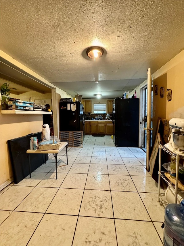 kitchen with a textured ceiling, light tile patterned flooring, and freestanding refrigerator