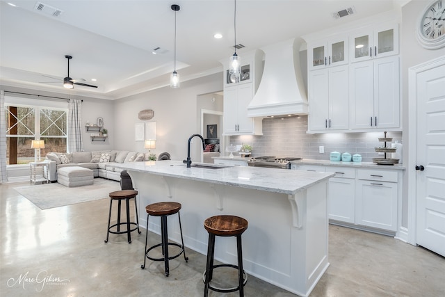 kitchen featuring premium range hood, range, a sink, and visible vents