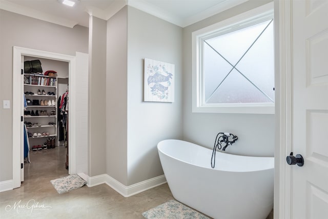 bathroom featuring concrete flooring, baseboards, a freestanding bath, a spacious closet, and crown molding