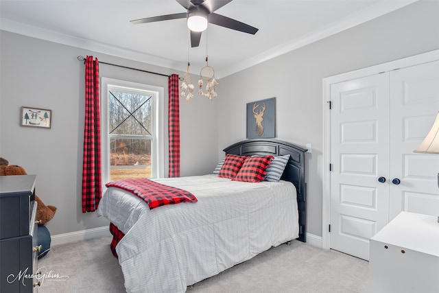 carpeted bedroom with baseboards, a closet, a ceiling fan, and crown molding